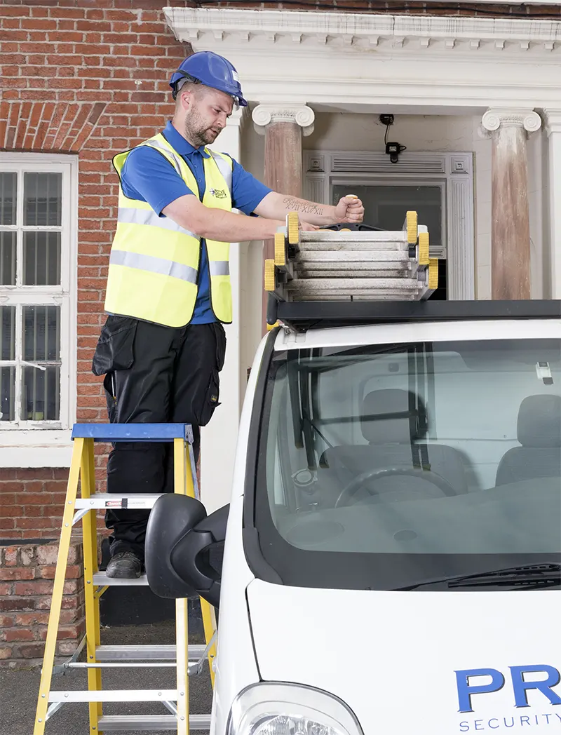 Protive security employee loading ladders onto the van